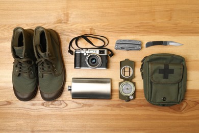Set of traveler's equipment on wooden table, flat lay