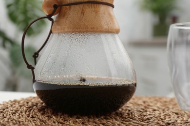 Glass chemex coffeemaker with coffee on table, closeup