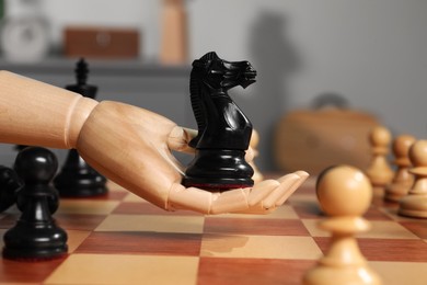 Photo of Robot with knight over chessboard, closeup. Wooden hand representing artificial intelligence