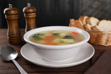 Photo of Tasty chicken soup with vegetables in bowl served on wooden table, closeup