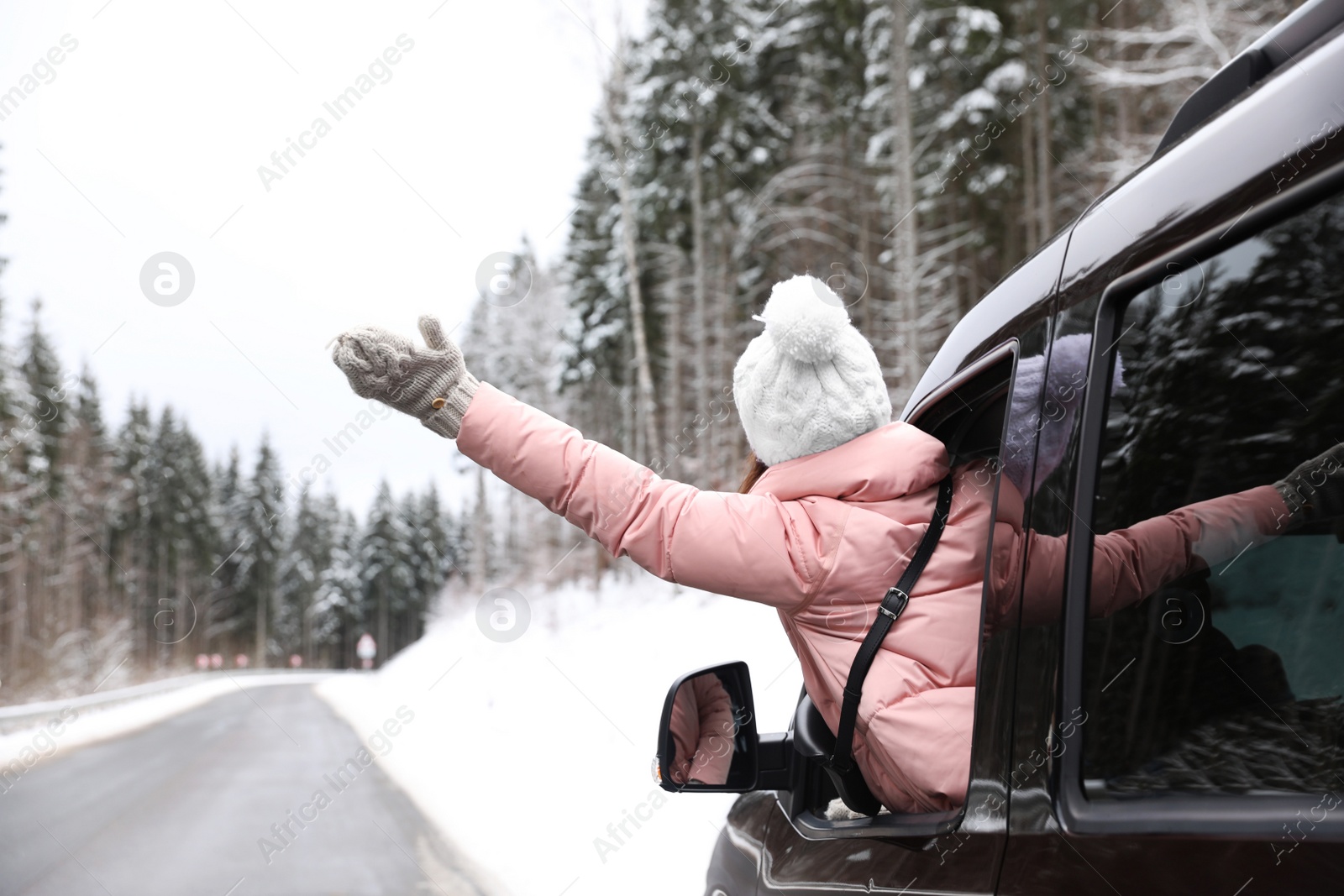 Photo of Young woman looking out of car window on road. Winter vacation