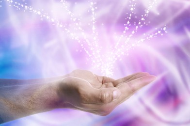 Image of Aura phenomena. Man with flows of energy around his hands and lights flying out against color background, closeup