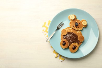 Photo of Creative serving for kids. Plate with cute bear made of pancakes, blueberries, bananas and chocolate paste on light wooden table, top view. Space for text