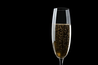 Photo of Glass of fizzy champagne on black background, closeup. Space for text