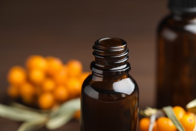 Photo of Natural sea buckthorn oil in bottle on blurred background, closeup