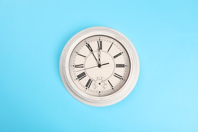 Photo of Stylish vintage wall clock showing five minutes until midnight on turquoise background, top view. New Year countdown