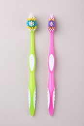 Colorful plastic toothbrushes on light background, flat lay