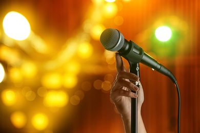 Photo of Woman with microphone against festive lights, closeup. Space for text