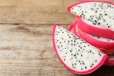 Photo of Slices of delicious dragon fruit (pitahaya) on wooden table, closeup. Space for text