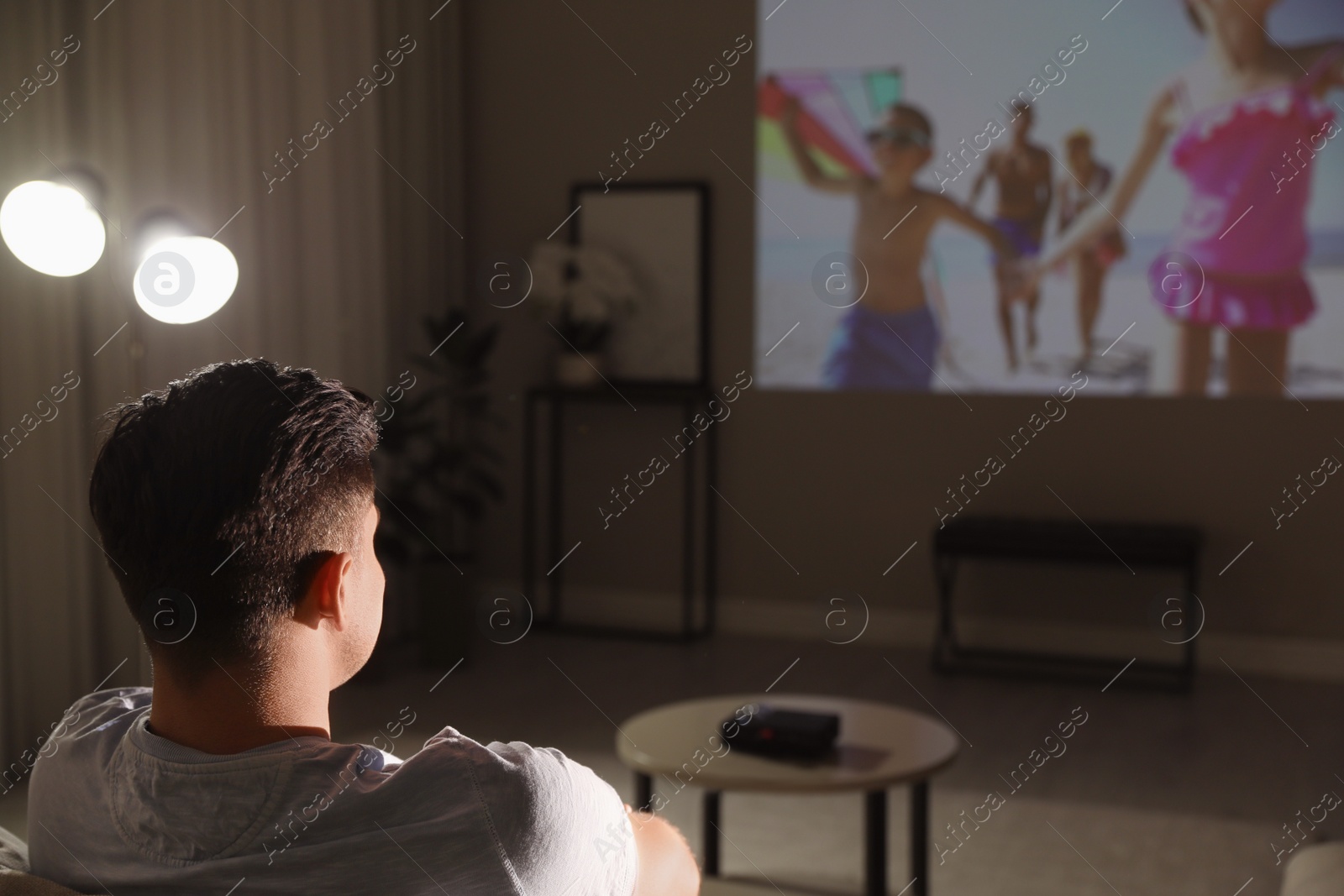 Photo of Man watching movie on sofa at night, back view. Space for text