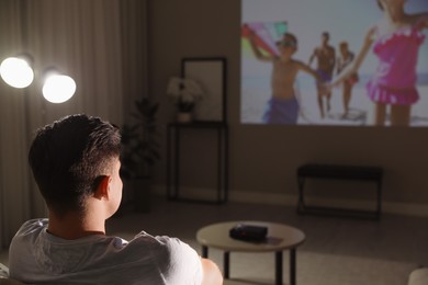 Photo of Man watching movie on sofa at night, back view. Space for text