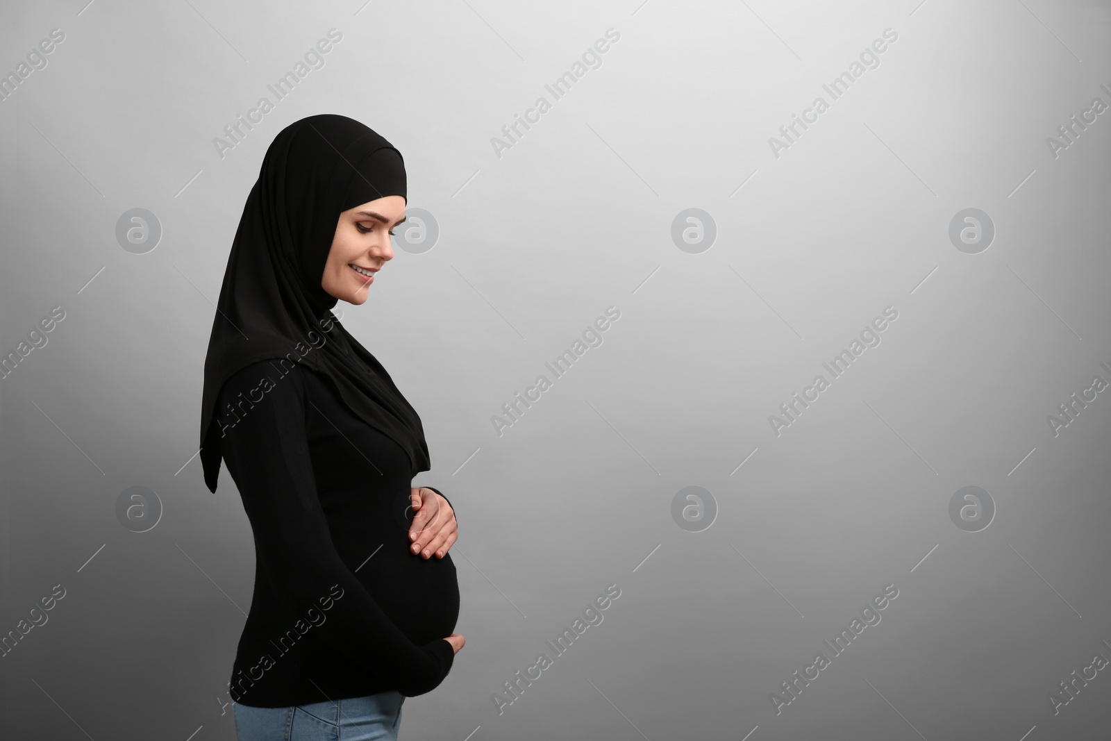 Photo of Portrait of pregnant Muslim woman in hijab on light gray background, space for text