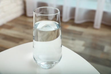 Glass of water on table in room. Refreshing drink