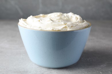 Photo of Bowl of tasty cream cheese on light grey table