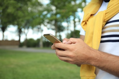 Photo of Man with smartphone in park on summer day, closeup