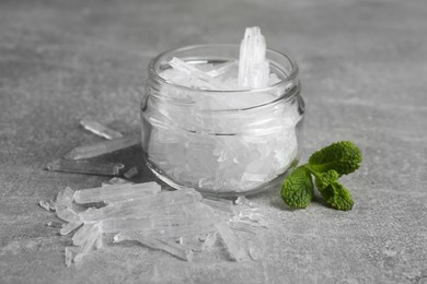 Photo of Menthol crystals and fresh mint leaves on grey background