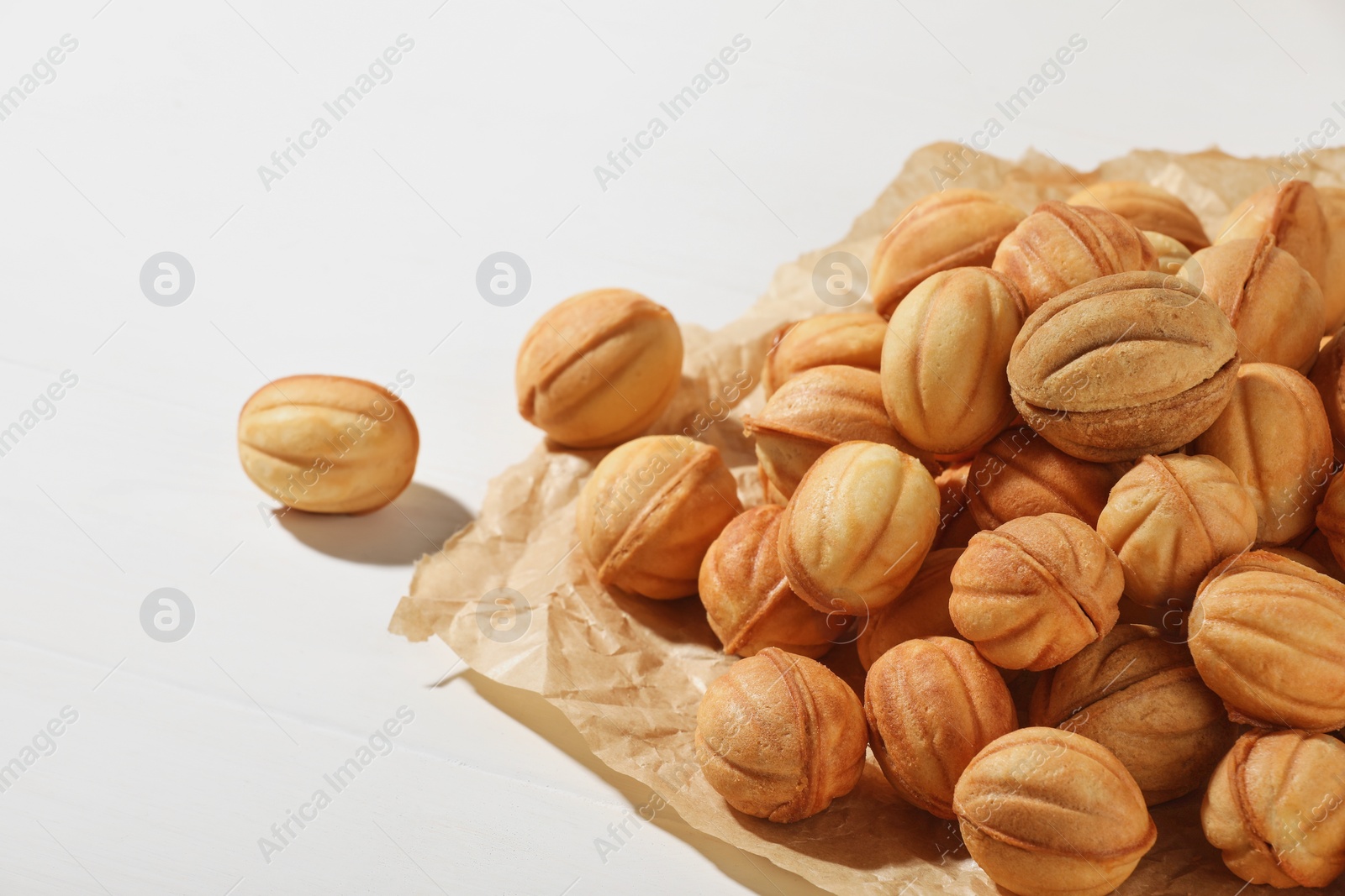 Photo of Freshly baked walnut shaped cookies on white wooden table, closeup and space for text. Homemade pastry filled with caramelized condensed milk