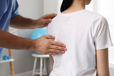 Orthopedist examining woman's back in clinic, closeup. Scoliosis treatment