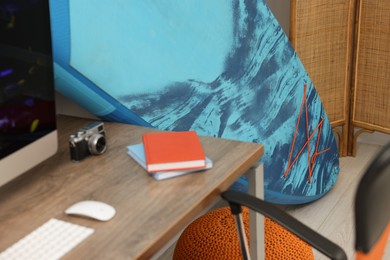 SUP board, books and camera on wooden table in room