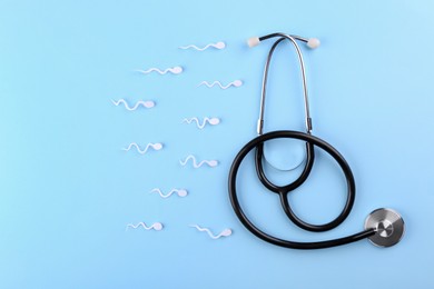 Reproductive medicine. Figures of sperm cells and stethoscope on light blue background, flat lay