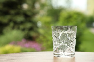 Photo of Glass of fresh water on wooden table outdoors, space for text