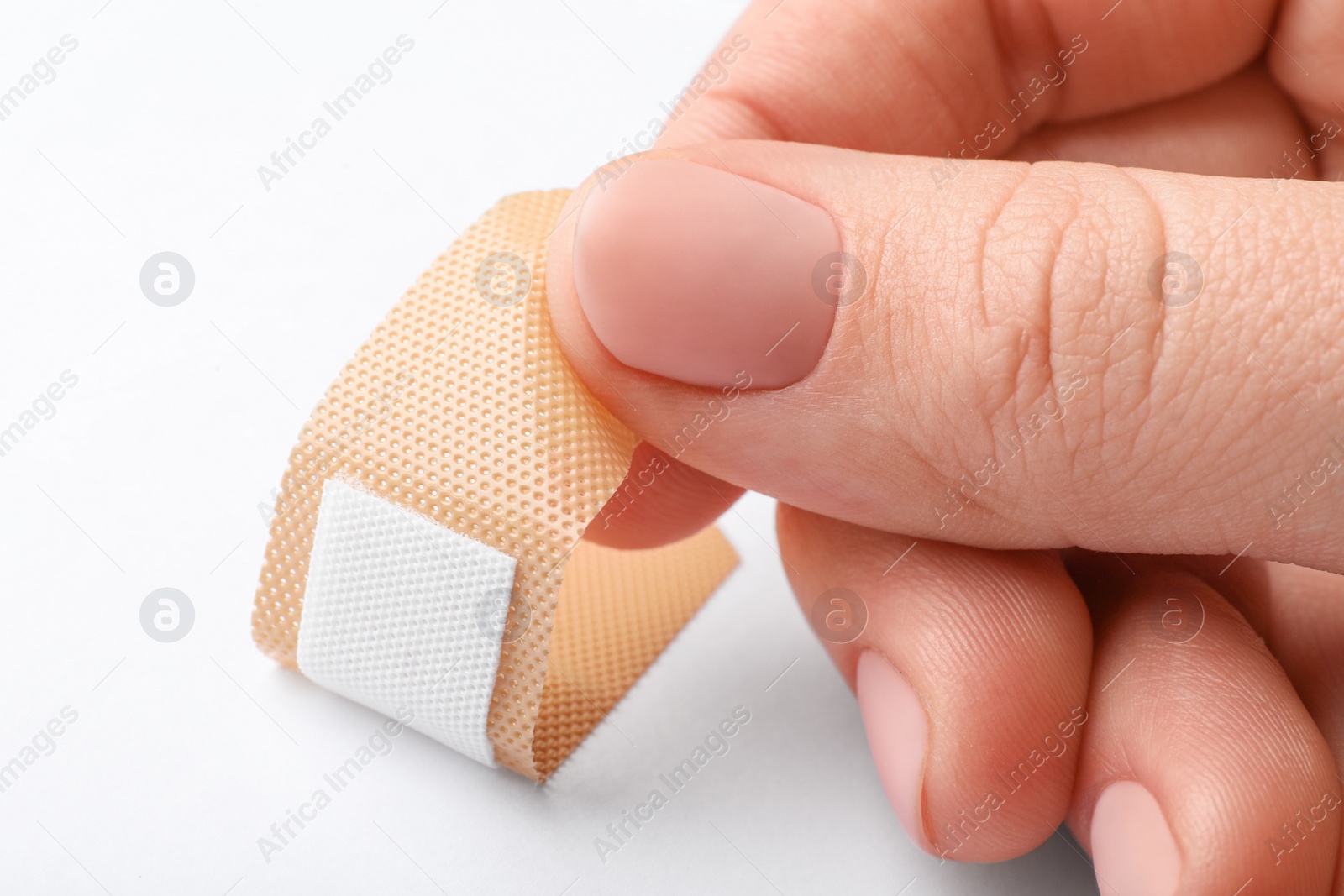 Woman putting sticking plaster on white background, closeup. First aid item Photo of Woman putting sticking plaster on white background, closeup. First aid item