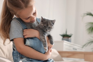 Photo of Cute little girl with kitten at home, space for text. Childhood pet
