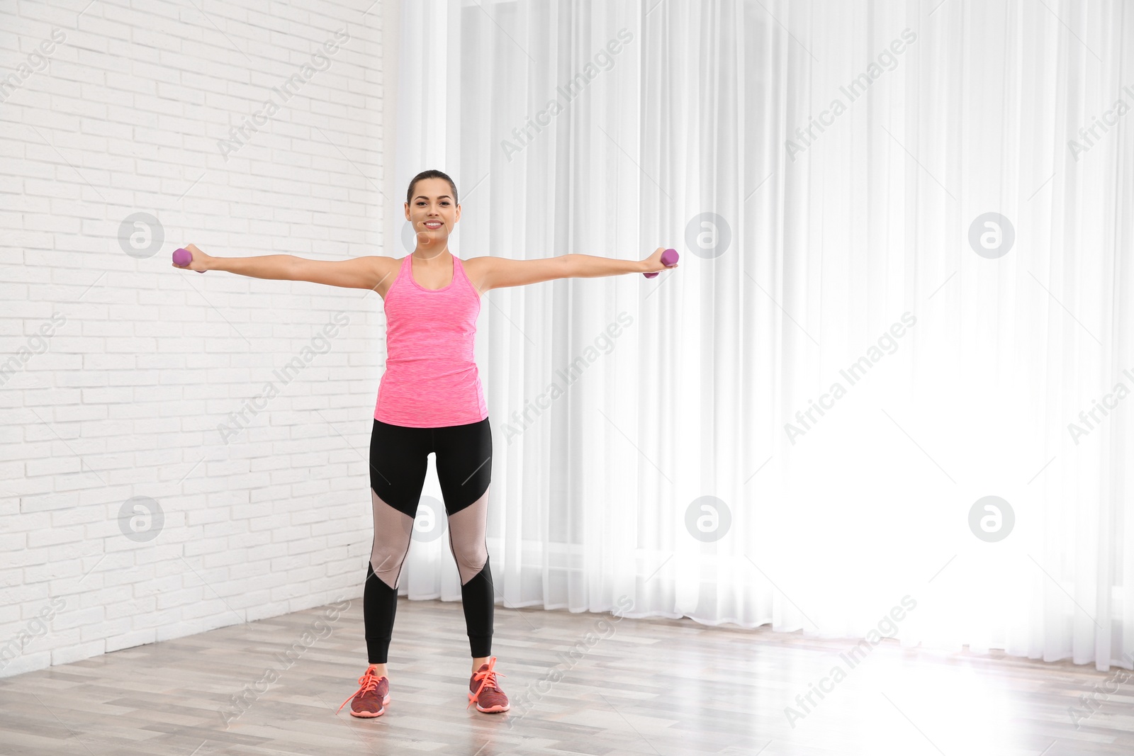 Photo of Young beautiful woman with dumbbells doing exercise at home, space for text. Workout and fitness