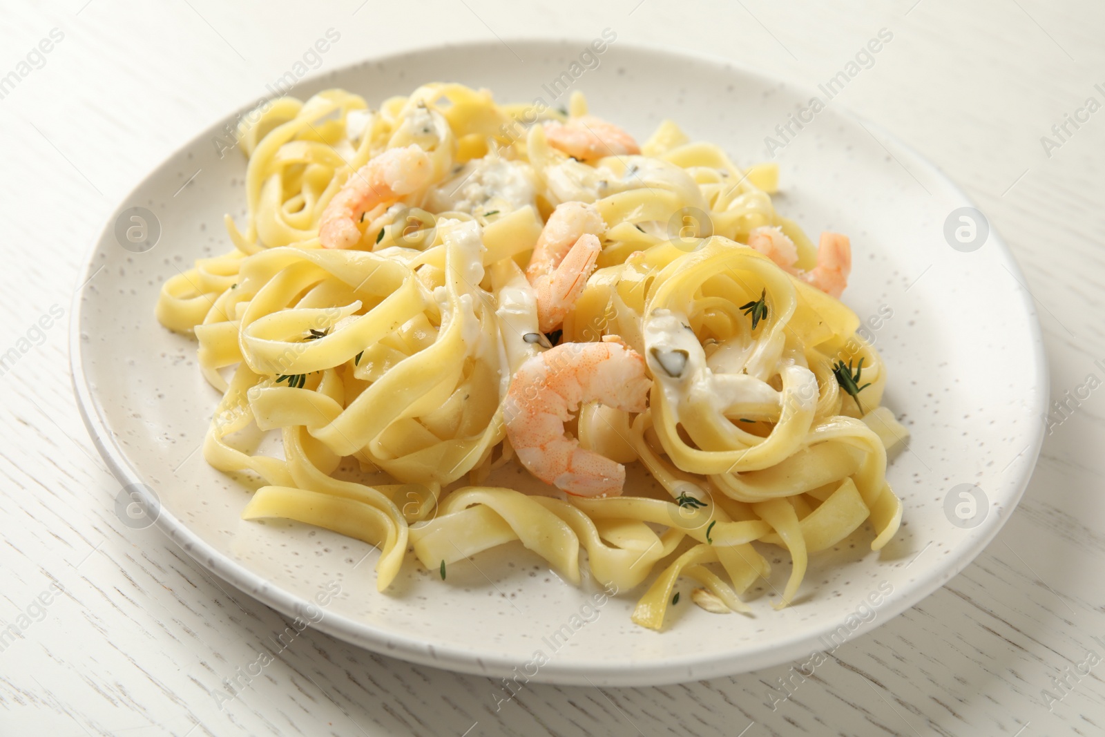 Photo of Delicious pasta with shrimps on white wooden table