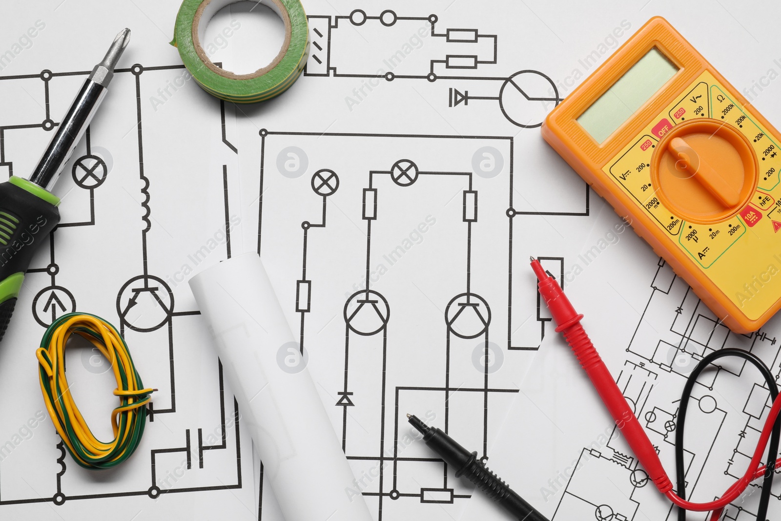 Photo of Digital multimeter and tools on wiring diagrams, top view