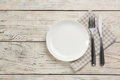 Photo of Empty plate, fork and knife on white wooden table, flat lay. Space for text