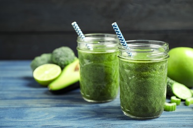 Delicious fresh green juice on blue wooden table. Space for text