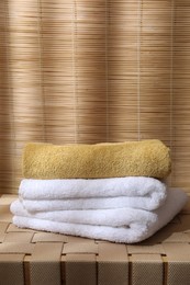 Stacked soft towels on wicker bench indoors