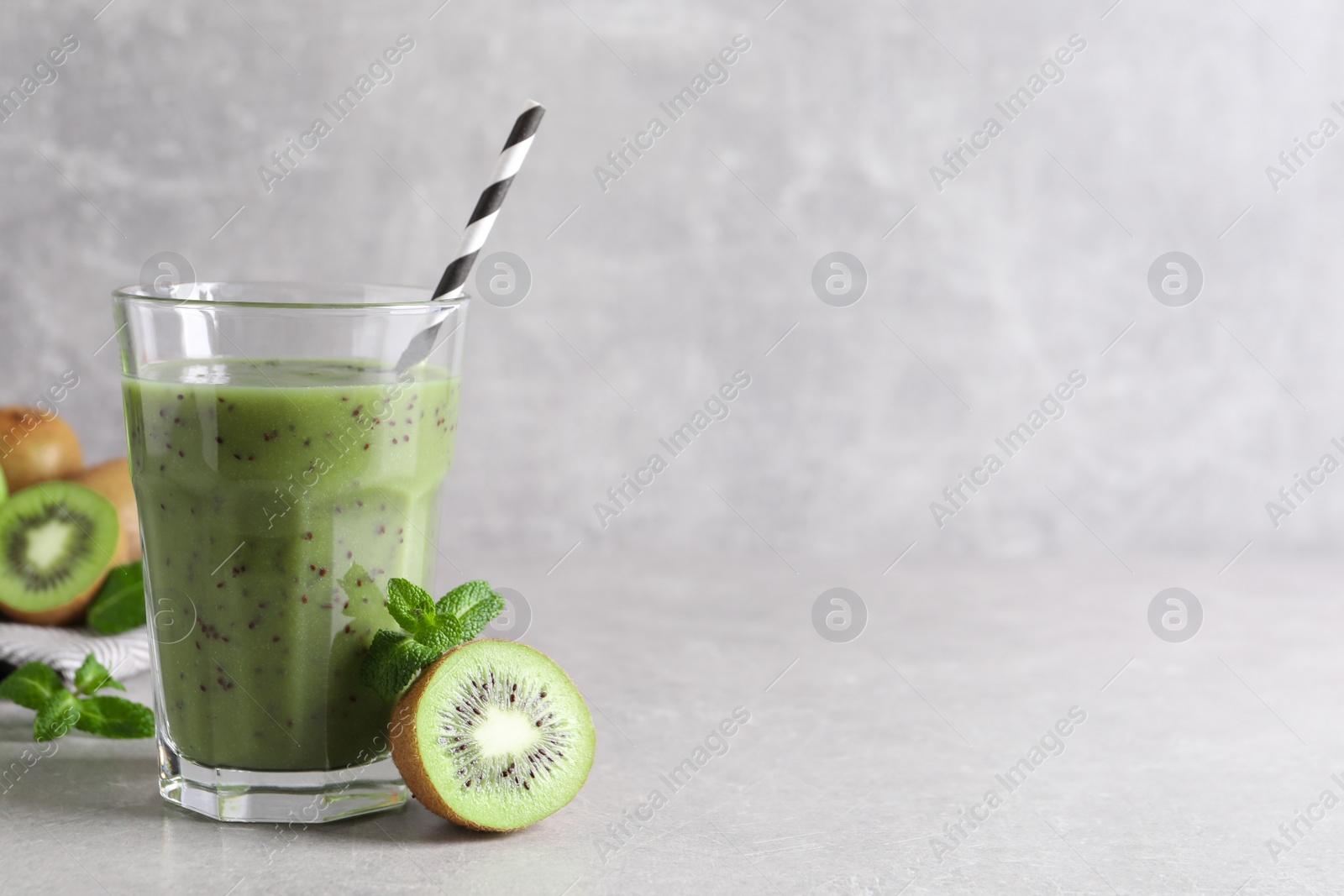 Photo of Delicious kiwi smoothie and fresh fruits on light grey table. Space for text