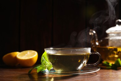 Cup of aromatic herbal tea and mint on wooden table