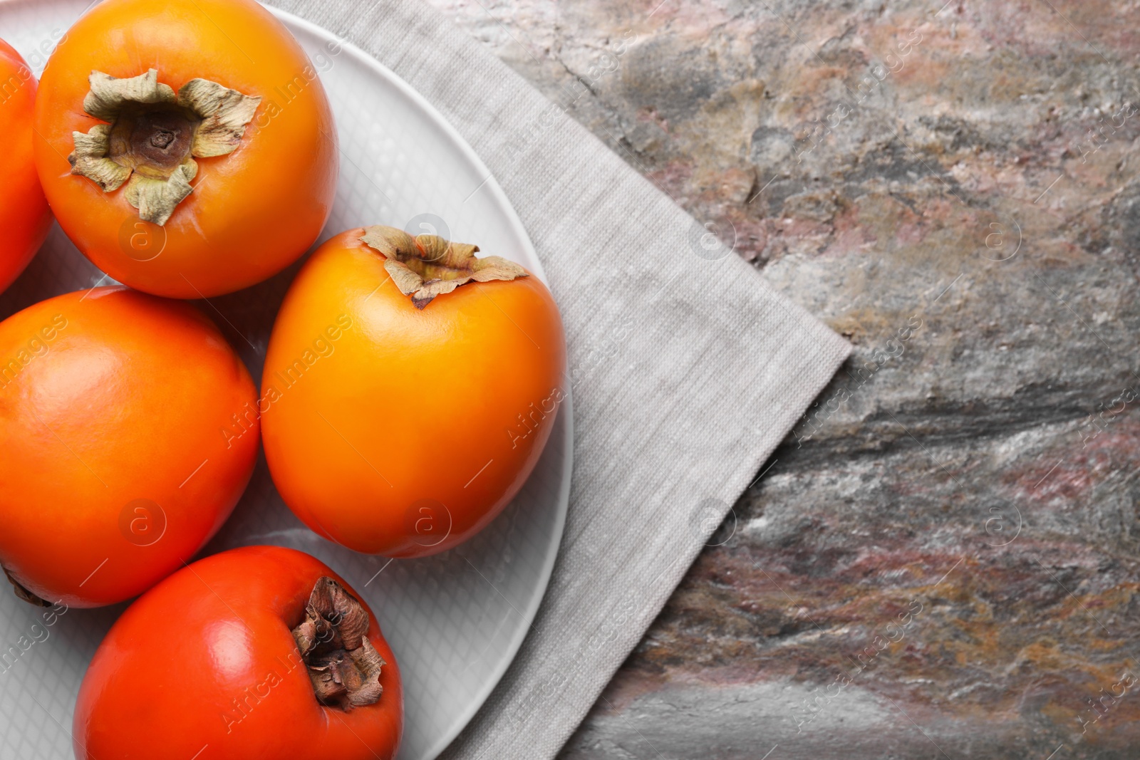 Photo of Delicious ripe persimmons on textured table, top view. Space for text