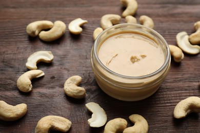 Photo of Delicious cashew butter and ingredient on wooden table, closeup