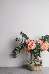Photo of Bouquet of beautiful flowers in glass vase on grey table against white background