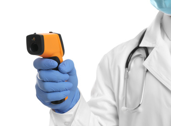 Doctor in latex gloves holding non contact infrared thermometer on white background, closeup. Measuring temperature