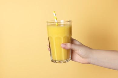 Photo of Woman holding glass of tasty smoothie on yellow background, closeup