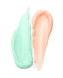 Photo of Strokes of pink and green color correcting concealers on white background, top view