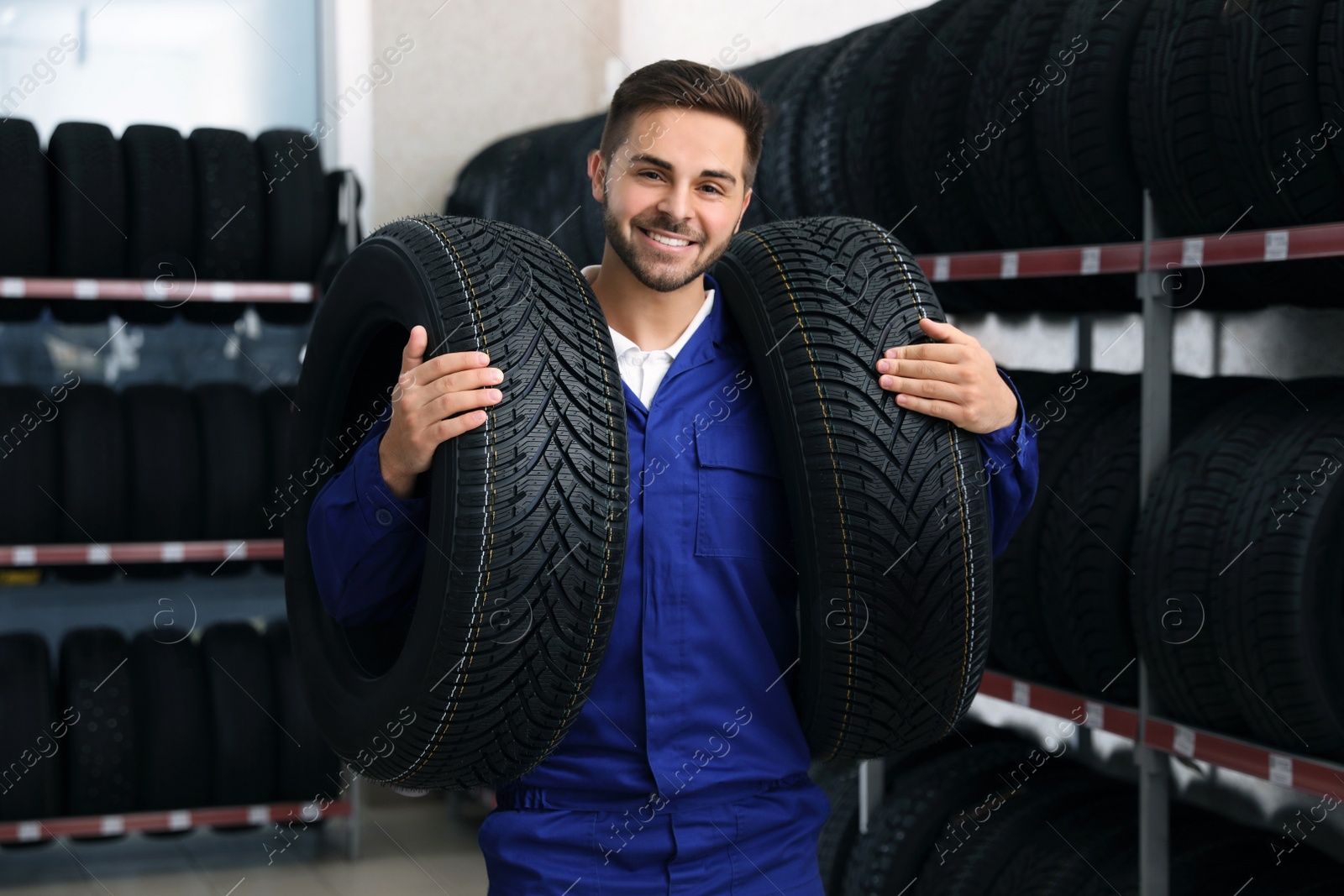 Photo of Male mechanic with car tires in auto store