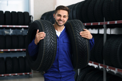 Male mechanic with car tires in auto store