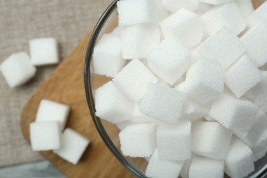 Photo of White sugar cubes in glass bowl on grey table, top view