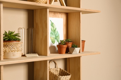 Wooden shelves with different decorative elements on beige wall,