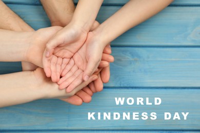 World Kindness Day. Parents and kid holding hands on light blue wooden table, top view