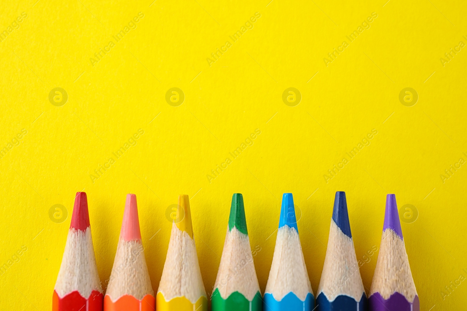 Photo of Colorful pencils on yellow background, flat lay with space for text. Rainbow palette