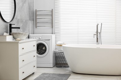 Photo of Stylish bathroom interior with heated towel rail and modern white tub