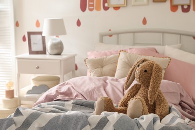Photo of Toy bunny on bed in child's room. Interior design