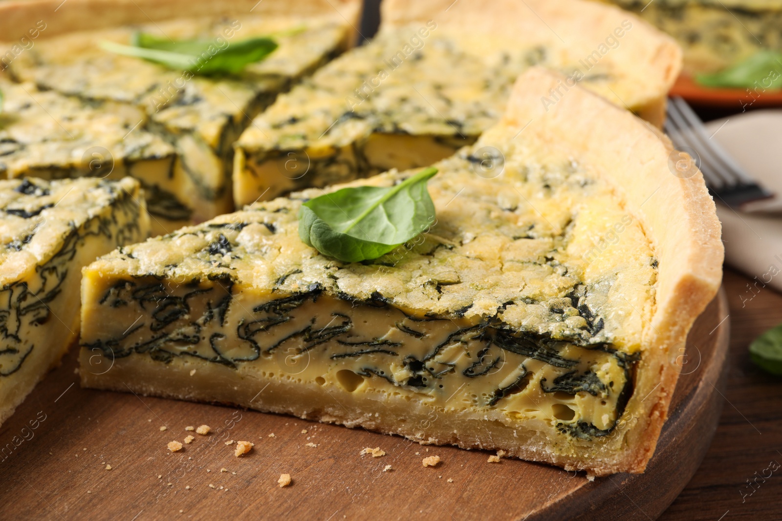 Photo of Cut delicious spinach pie on wooden board, closeup